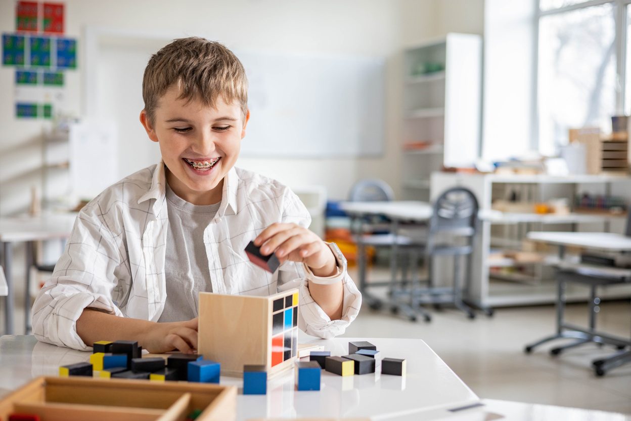 A group of children joyfully raising their hands in a classroom setting